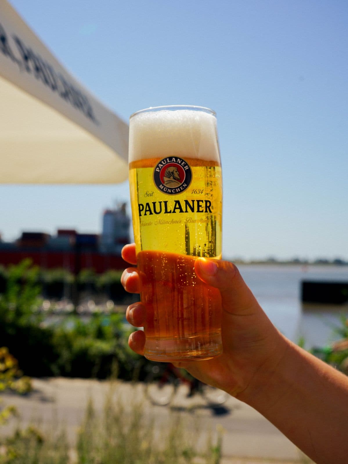 Frisch gezapftes Bier vor der Elbe mit Containerschiff