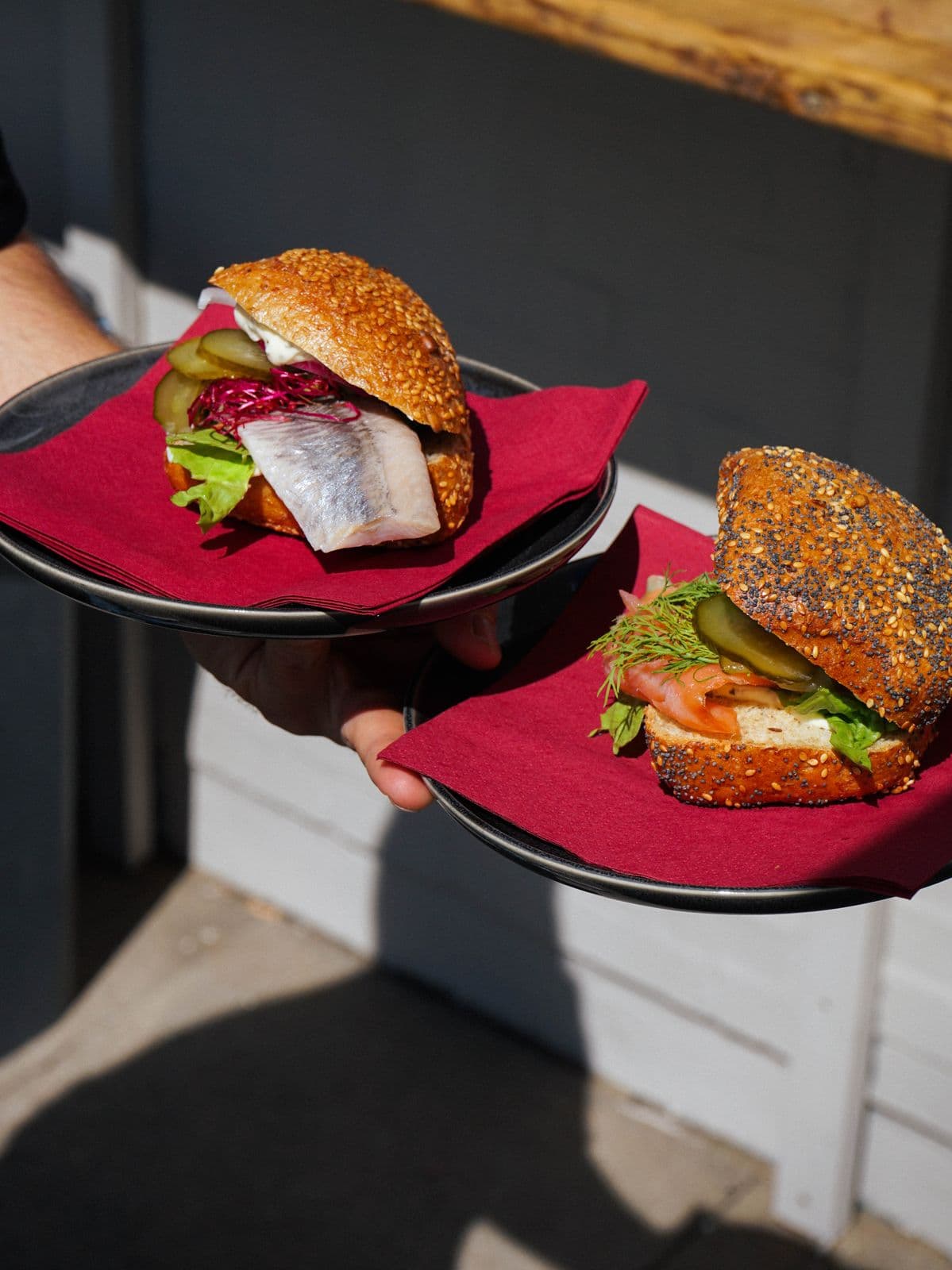 Zwei Fischbrötchen mit Matjes und Lachs werden auf Tellern gereicht