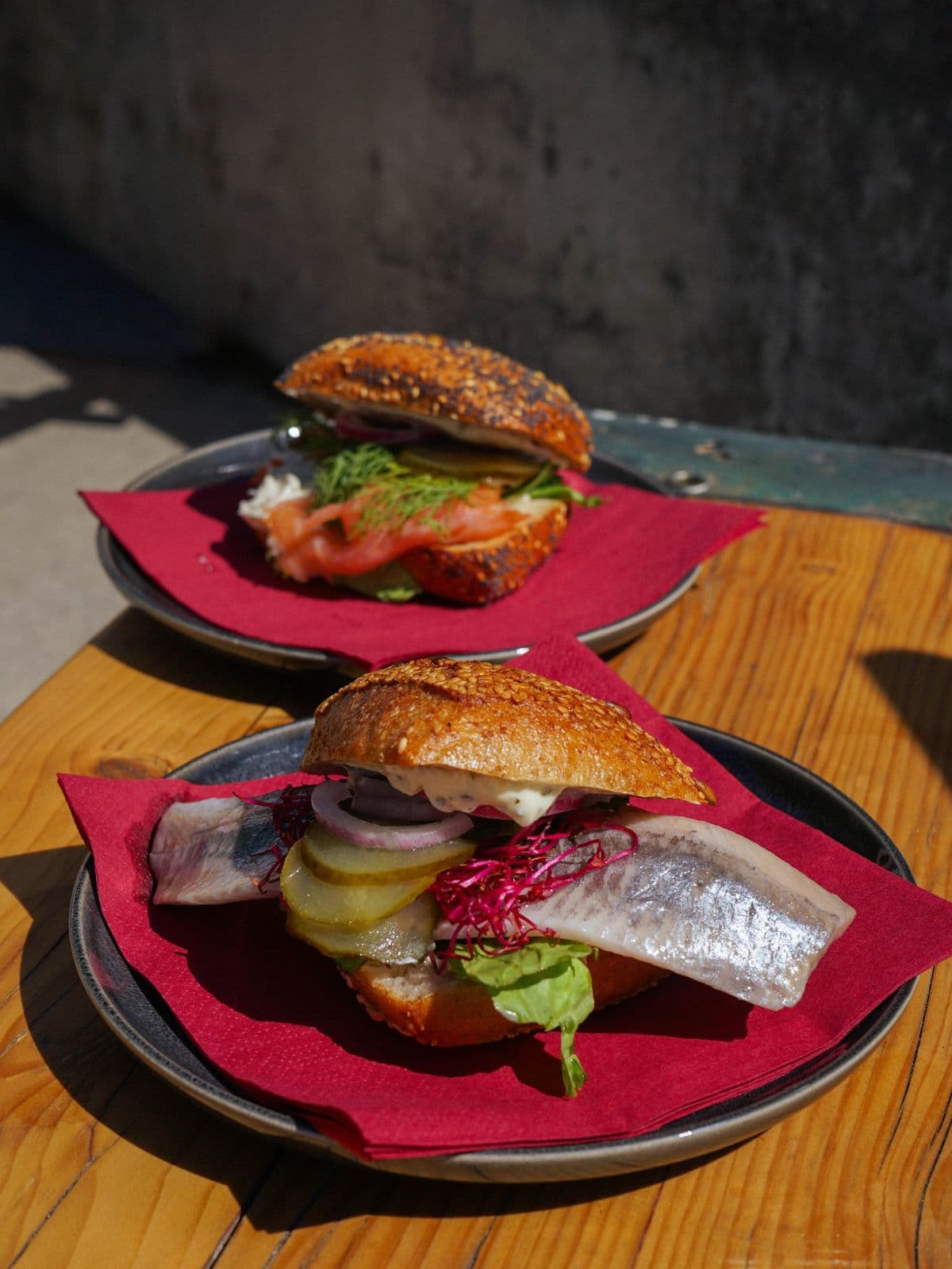 Zwei Fischbrötchen mit Matjes und Lachs auf dunklen Tellern