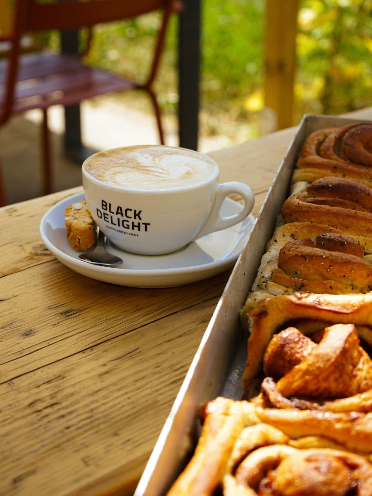 Cappuccino neben einem Blech Zimtschnecken